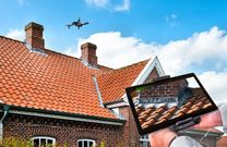 Drone carrying out an aerial roof inspection over a UK residential property